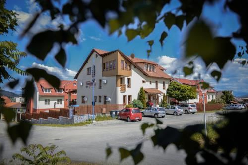 a house with cars parked in a parking lot at Pension Panorama in Odorheiu Secuiesc