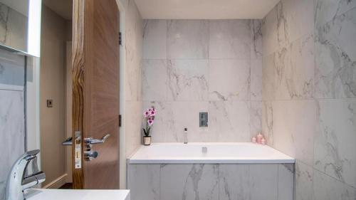 a bathroom with a white tub and marble walls at Castle Penthouse in Deganwy
