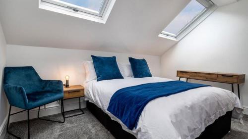 1 dormitorio con cama con almohadas azules y escritorio en Station Loft, en Deganwy
