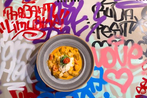 a bowl of food on a wall with graffiti at ibis Budapest Castle Hill in Budapest