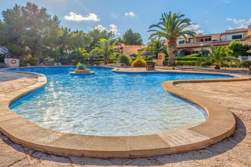 a pool in a resort with palm trees at Can Om in Campos