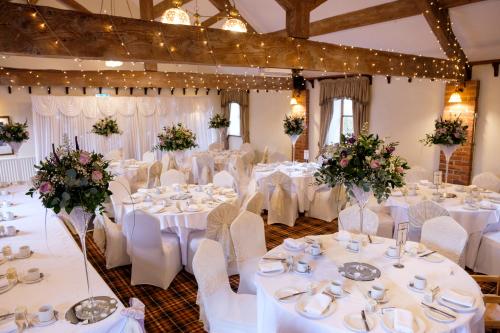 a banquet hall with white tables and chairs and flowers at Slaters Country Inn in Whitmore