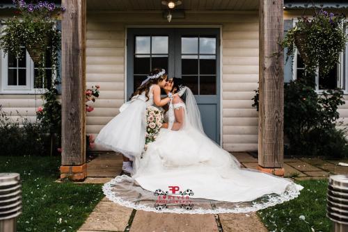 Una novia y un novio besándose delante de una casa en Slaters Country Inn, en Whitmore