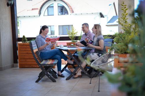 a group of people sitting at a table on a patio at Pension Panorama in Odorheiu Secuiesc