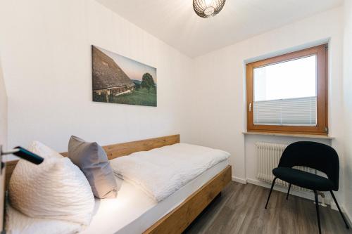 una camera con un letto e una sedia e una finestra di Moderne 3 Zi.-FeWo BlackForest Art Nähe Freiburg a Simonswald