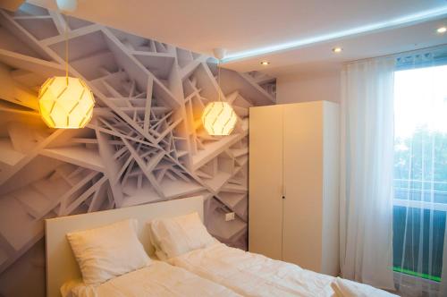 a bedroom with a bed and two lights on the wall at Apartament Mirek in Łódź