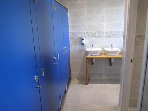 a bathroom with two sinks and a blue door at Albergue Centro de Ocio Luis Miguel in Fresno de la Fuente