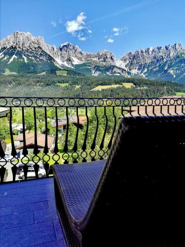 a bench on a balcony with a view of mountains at Hotel Hochfilzer in Ellmau