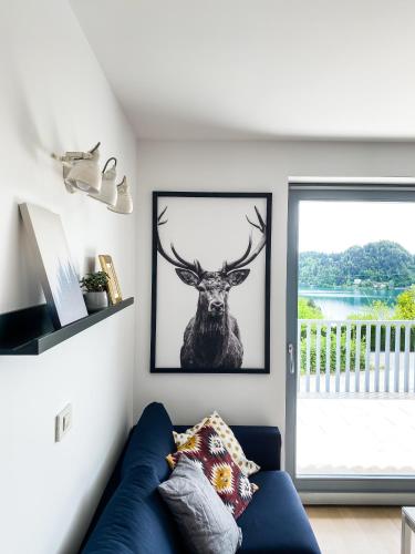 a living room with a blue couch and a picture of a deer at Lakeview Villa Bled in Bled