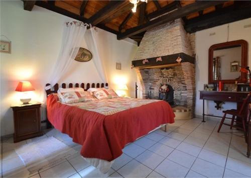 ein Schlafzimmer mit einem großen Bett und einem Steinkamin in der Unterkunft LE GAHOUN - Chambres d'hôtes in Castets