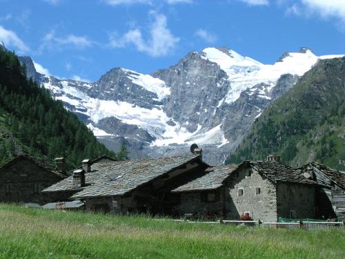 a group of buildings in front of a snow covered mountain at Hotel Restaurant La Barme in Cogne