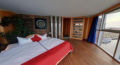 a red and white bed in a room with a window at Speicher Barth - Superior-Hotel in Barth