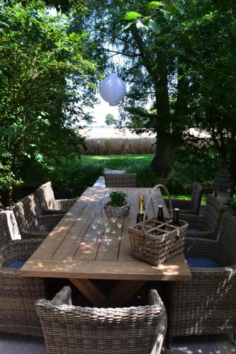 einen Holztisch mit Korbstühlen und einen Tisch mit Weingläsern in der Unterkunft Bellefleur in Veurne