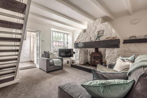 a living room with a couch and a stone fireplace at Lime Kiln Cottage, Pentewan, Cornwall in Pentewan