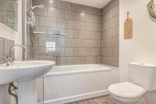 a bathroom with a tub and a toilet and a sink at Lime Kiln Cottage, Pentewan, Cornwall in Pentewan