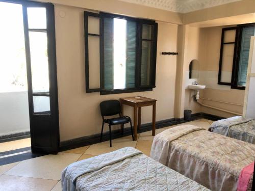 um quarto com duas camas e uma cadeira e uma mesa em Hotel El Maghreb Al Kabir em Nador