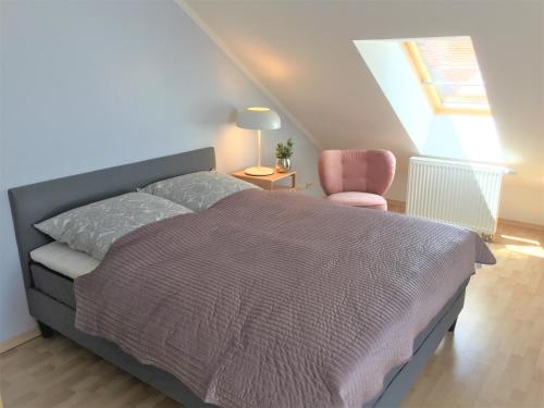 een slaapkamer met een bed en een roze stoel bij Zwillingsperlen Leutzsch - Appartement Villenblick in Leipzig