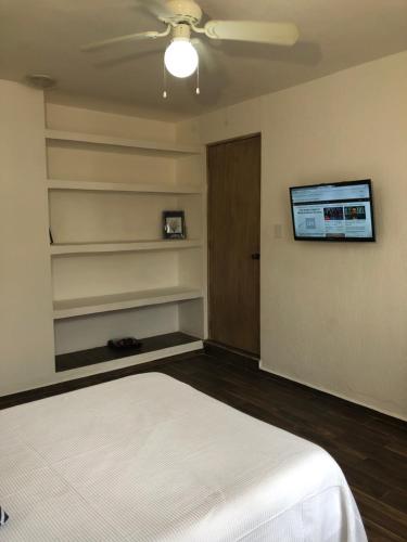 a bedroom with a bed and a tv on the wall at Casa Nova! PRIVATE BATHROOM AND ROOM in Cancún