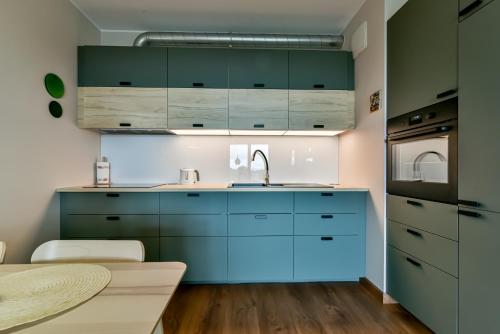 a kitchen with blue cabinets and a sink at LTC Apartments Silva in Gdynia