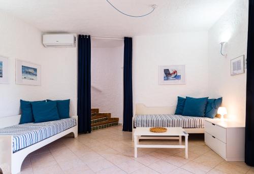 uma sala de estar com duas camas e uma mesa em La Rotonda Cottages - Klodge em Cala Bitta