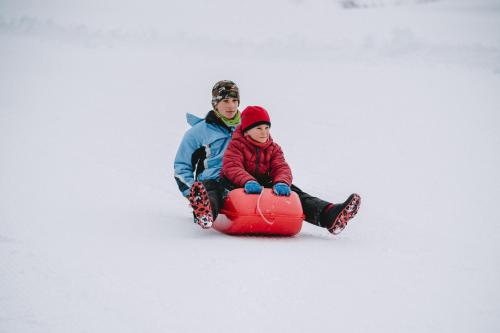 a man and a woman riding on a sled in the snow at Rifugio Cereda in Fiera di Primiero