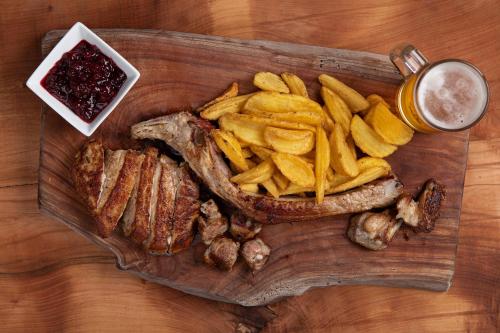 a wooden cutting board with meat and french fries at Rifugio Cereda in Fiera di Primiero