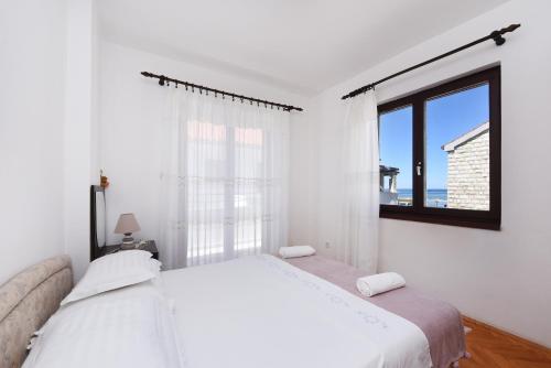 una camera bianca con un grande letto e una finestra di Apartment Sonja a Zaton