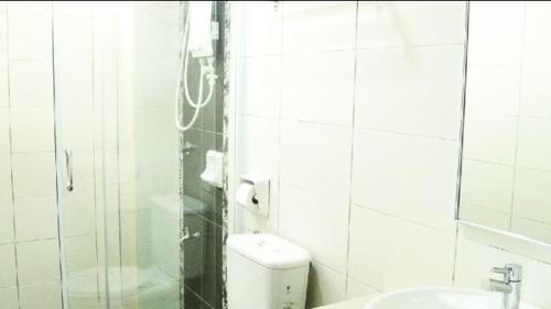 a white tiled bathroom with a toilet and a sink at Marina Height Seaview Resort, Teluk Batik, Lumut in Kampong Tebing Rabak