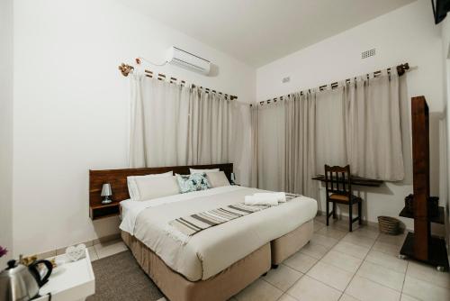 a bedroom with a bed and a table and a chair at Wonna Bay Vila Lodge-Catembe in Maputo