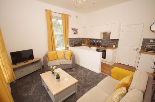 a living room with a couch and a kitchen at Grosvenor Lodge Birkdale Southport in Southport