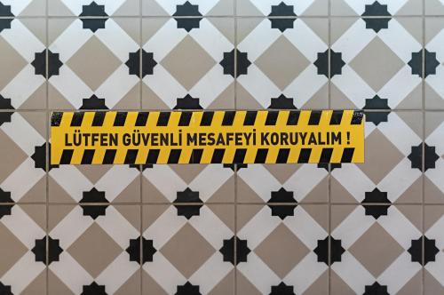 a yellow and black sign on a tiled wall at Atrium Taş Otel in Cesme