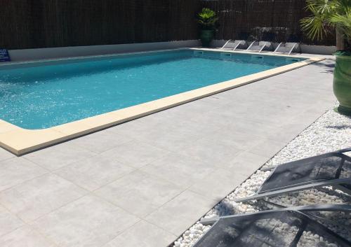a swimming pool in a yard with chairs around it at HOTEL ERMITAGE in Les Angles Gard