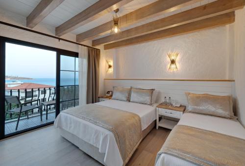 um quarto de hotel com duas camas e uma varanda em Atrium Taş Otel em Cesme