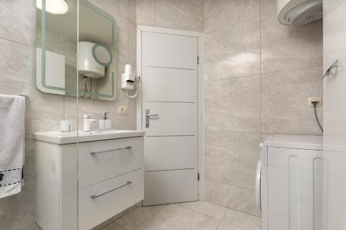 a white bathroom with a sink and a mirror at Studio Apartman Nega 3 in Rovinj