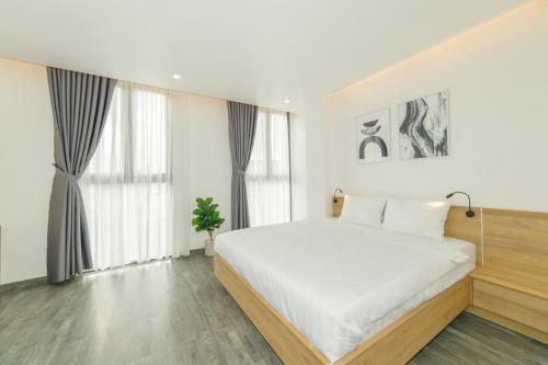 a white bedroom with a large bed and windows at CIEN hotel in Quy Nhon