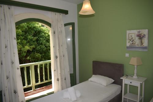 um quarto com uma cama e uma janela com uma varanda em Bellevue Apartments em Sitia