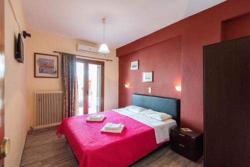 a red bedroom with a bed with two towels on it at Domus Inn in Ioannina