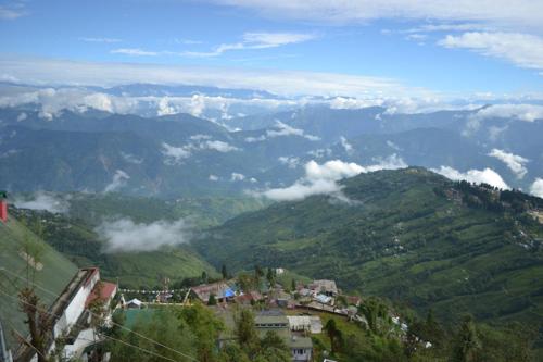 una vista de una ciudad en una montaña con nubes en The Retreat, en Darjeeling