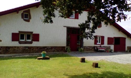 Casa blanca con ventanas rojas y maceta en Lastalia, en Ilharre