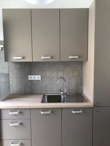uma cozinha com armários brancos e um lavatório em Avas Apartman em Miskolc
