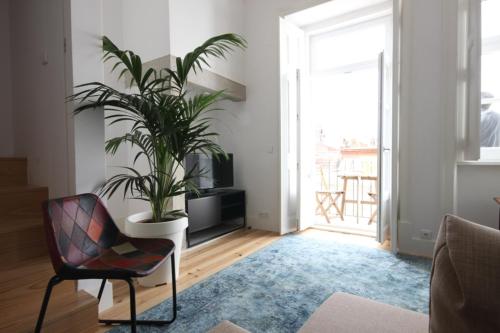 a living room with a potted plant and a chair at The Lookout Duplex - Bairro Alto in Lisbon