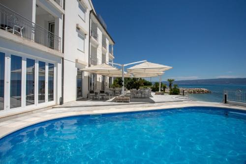 a swimming pool in front of a house with a view of the water at Hotel Neva in Podstrana