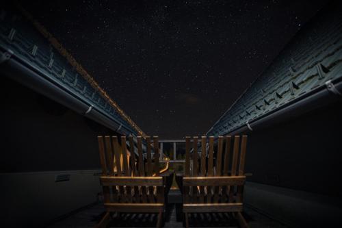 two chairs sitting on a balcony under a starry sky at Hotel Boka in Bovec