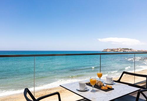a table with drinks and a plate of food on the beach at North Coast Seaside Suites in Rethymno