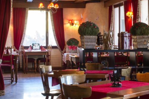 un comedor con mesas, sillas y cortinas rojas en Hôtel de charme la Poste, en Anzère