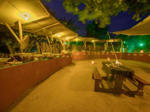 a patio with a bench and a table at night at Nkambeni Safari Camp in Hazyview