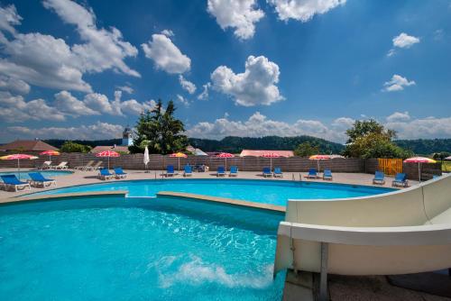 - une piscine dans un complexe avec des chaises et des parasols dans l'établissement Les Loges du Jura 4 étoiles, à Prénovel