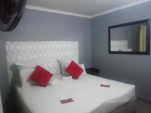 a bedroom with a white bed with red pillows at FGM Guesthouse 2 in Alberton