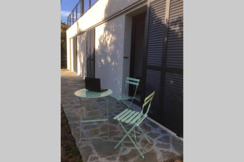 a table and a chair sitting on a patio at Villa Fogata à l'Ile Rousse vue mer exceptionnelle in LʼÎle-Rousse