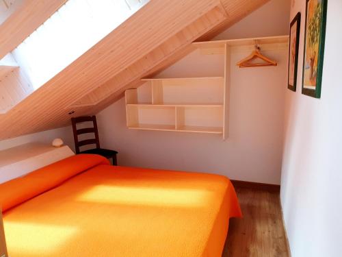 a bedroom with an orange bed in a attic at Apartamentos Casa Patro in Tramacastilla de Tena